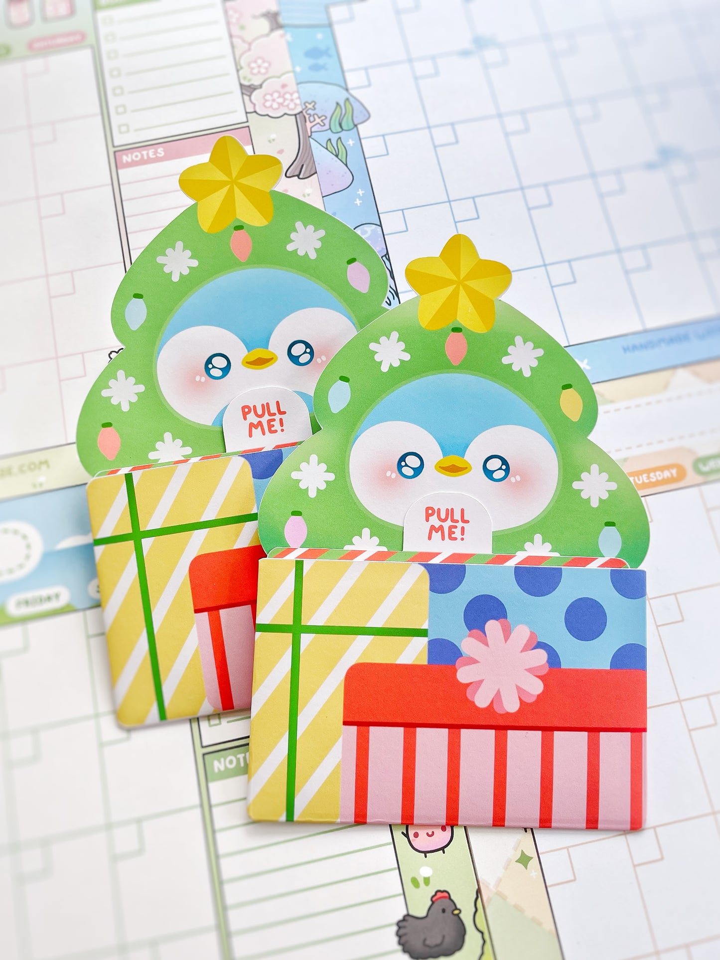 Two cartoon penguin-shaped gift cards with colorful designs on a planner background.
